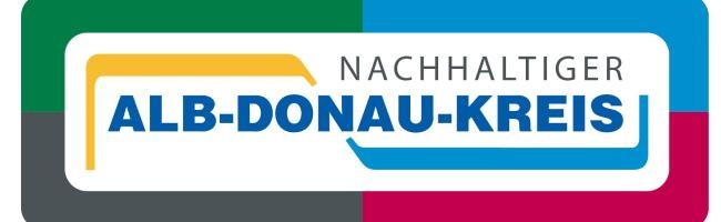 Hier ist das Logo des Alb-Donau-Kreises mit dem Schriftzug "Nachhaltiger Alb-Donau-Kreis zu sehen. Der Hintergrund ist aufgeteilt in vier quadratische Farbfelder in grün, blau, schwarz und rot.